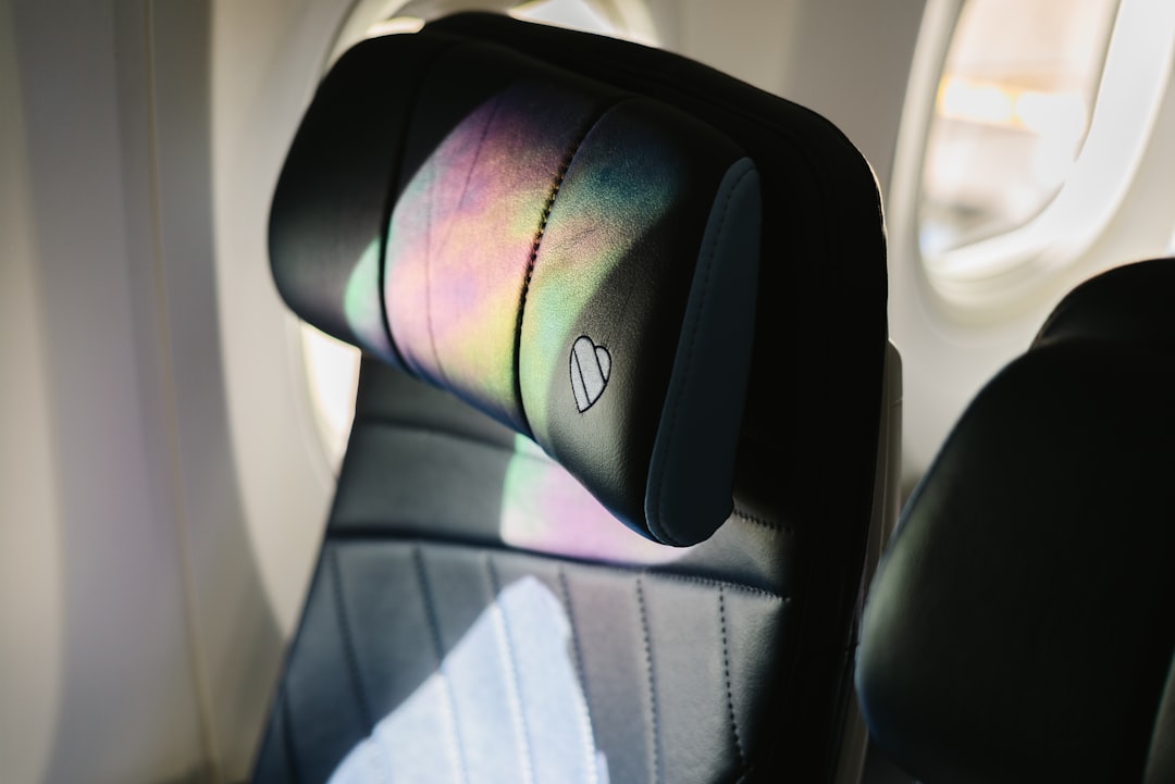 長時間フライトで快適に眠るためのネックピローとアイマスクが置かれた機内シート