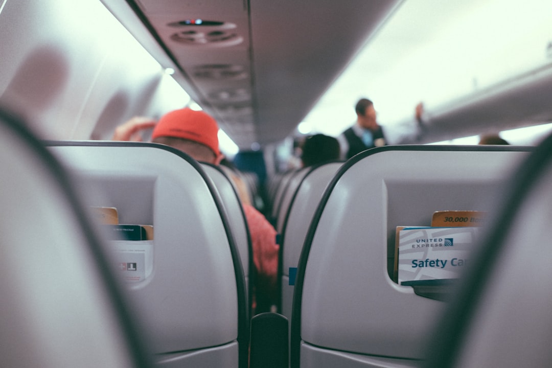 飛行機の機内で前席テーブルに掛けたフットレストに足を乗せて休む旅行者